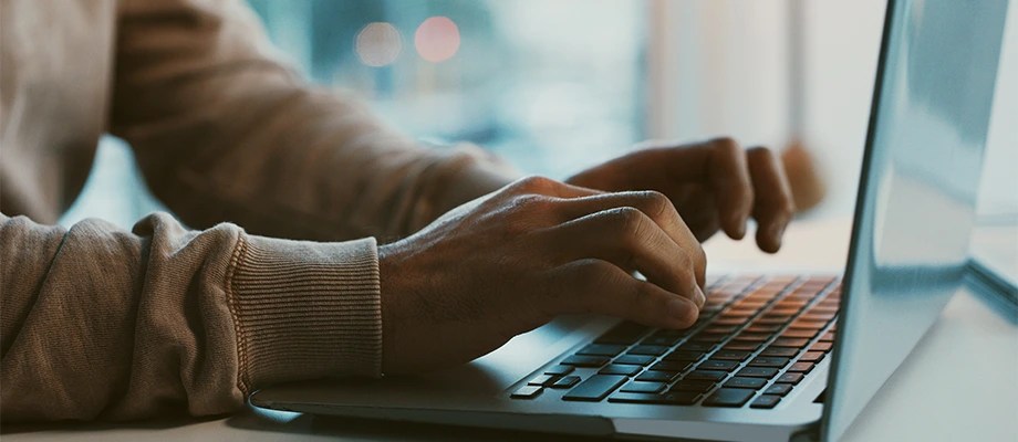 Persoană utilizând un laptop pentru documentare și gestionarea rețelelor electrice online.