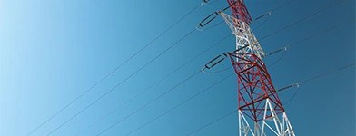 Stâlp de înaltă tensiune vopsit în roșu și alb, pe un fundal de cer albastru.