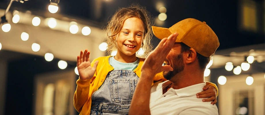 Tată și fiică sub lumini de exterior.