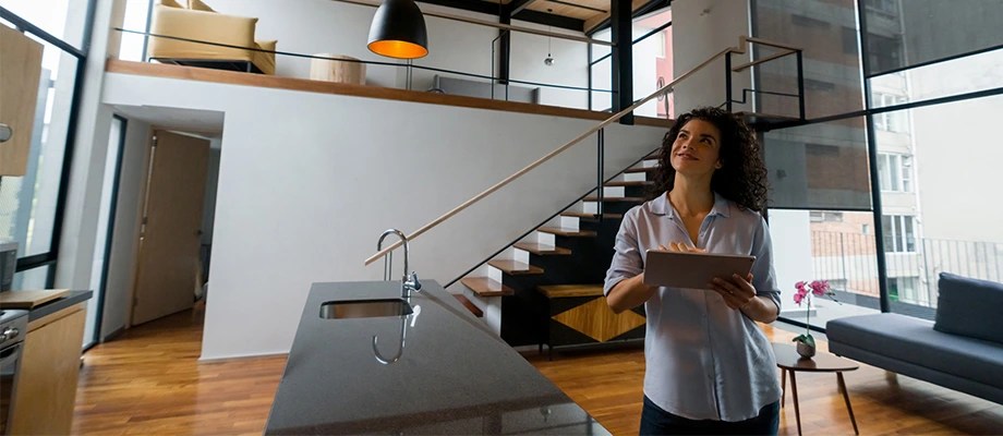 Femeie care consultă documente pe tabletă în casă, legat de instalația electrică.