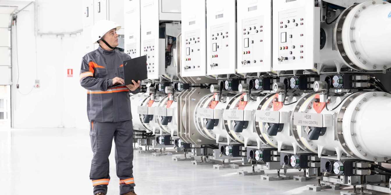 Tehnician în echipament de protecție lângă echipamente moderne de distribuție.