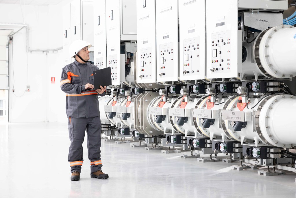 Technician in protective gear next to modern distribution equipment.