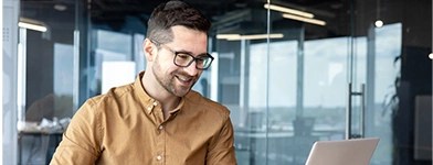 Bărbat care lucrează pe laptop într-un birou modern.