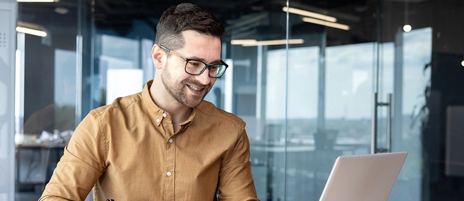 Bărbat care lucrează pe laptop într-un birou modern.