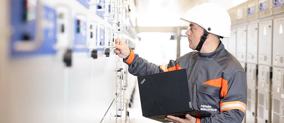 Tehnician in echipament de protectie verificand panouri electrice intr-o statie de distributie