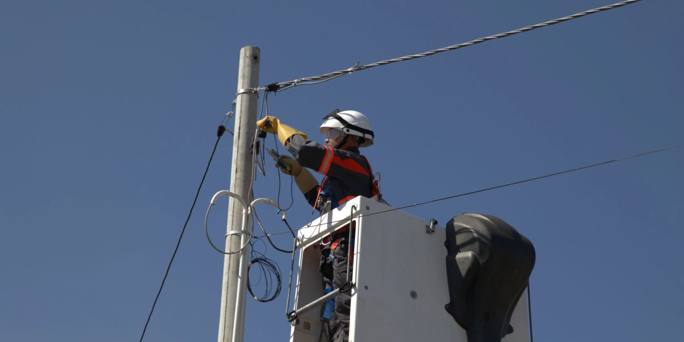An electrician elevated in a bucket lift to install or repair power lines.