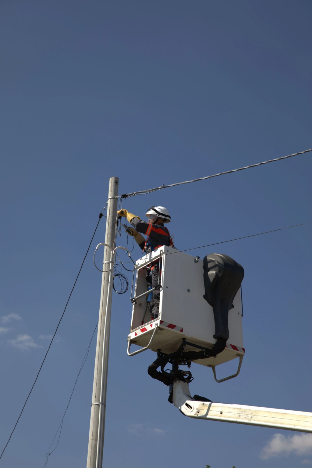 An electrician elevated in a bucket lift to install or repair power lines.