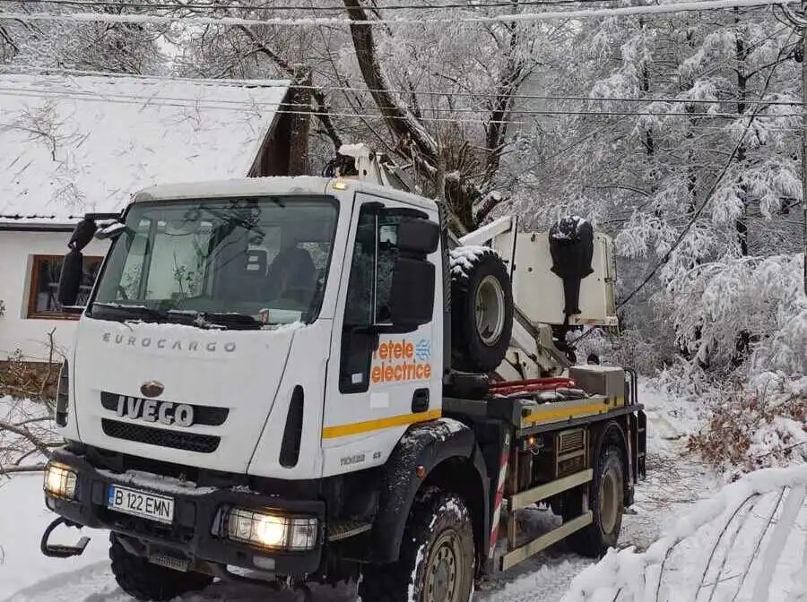 Camion care circulă pe un drum înzăpezit pentru a interveni și a remedia defecțiuni cauzate de o furtună de iarnă.