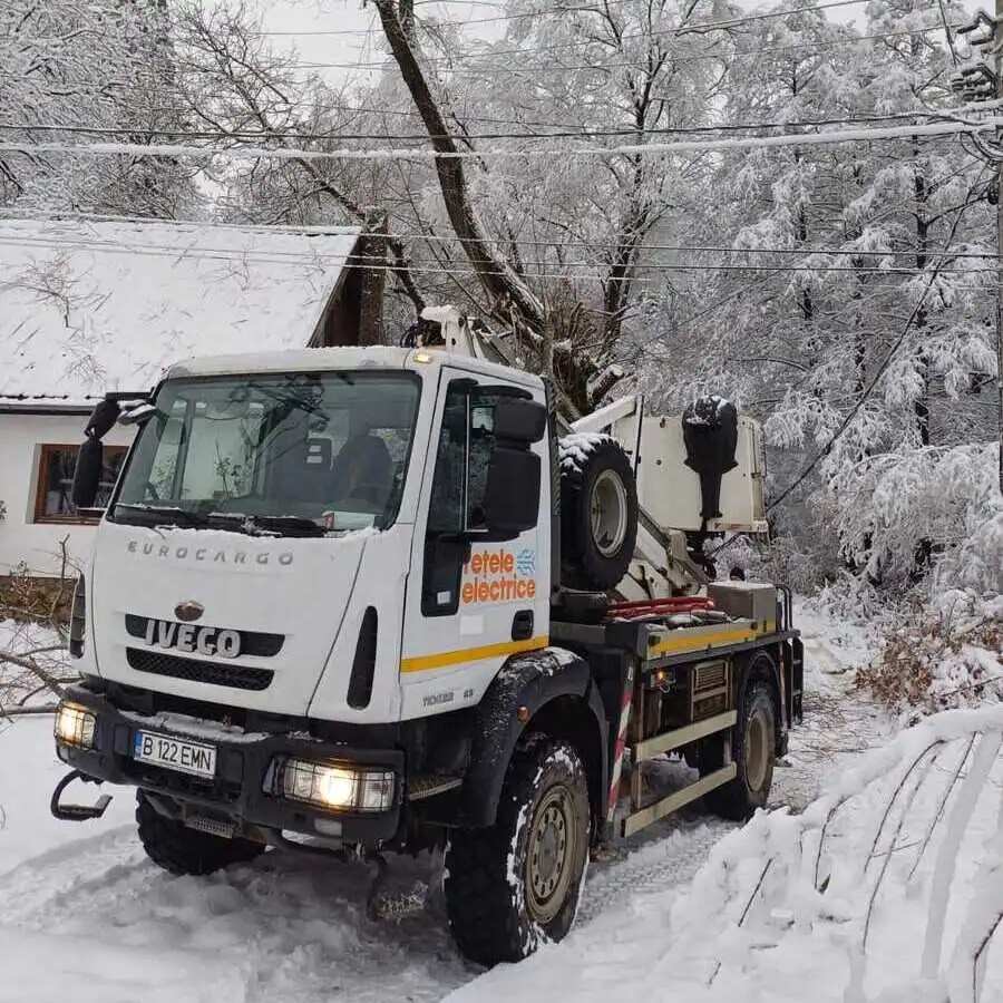 Camion care circulă pe un drum înzăpezit pentru a interveni și a remedia defecțiuni cauzate de o furtună de iarnă.