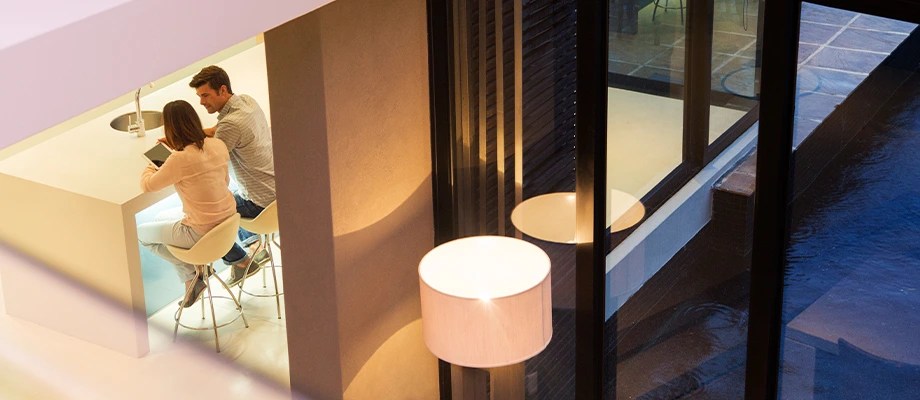 Femeie și bărbat într-o bucătărie iluminată puternic.