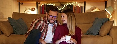 Cuplu care se relaxează într-un living confortabil, iluminat ambiental eficient.