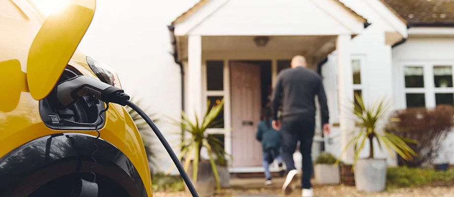 Yellow electric car charging at home.