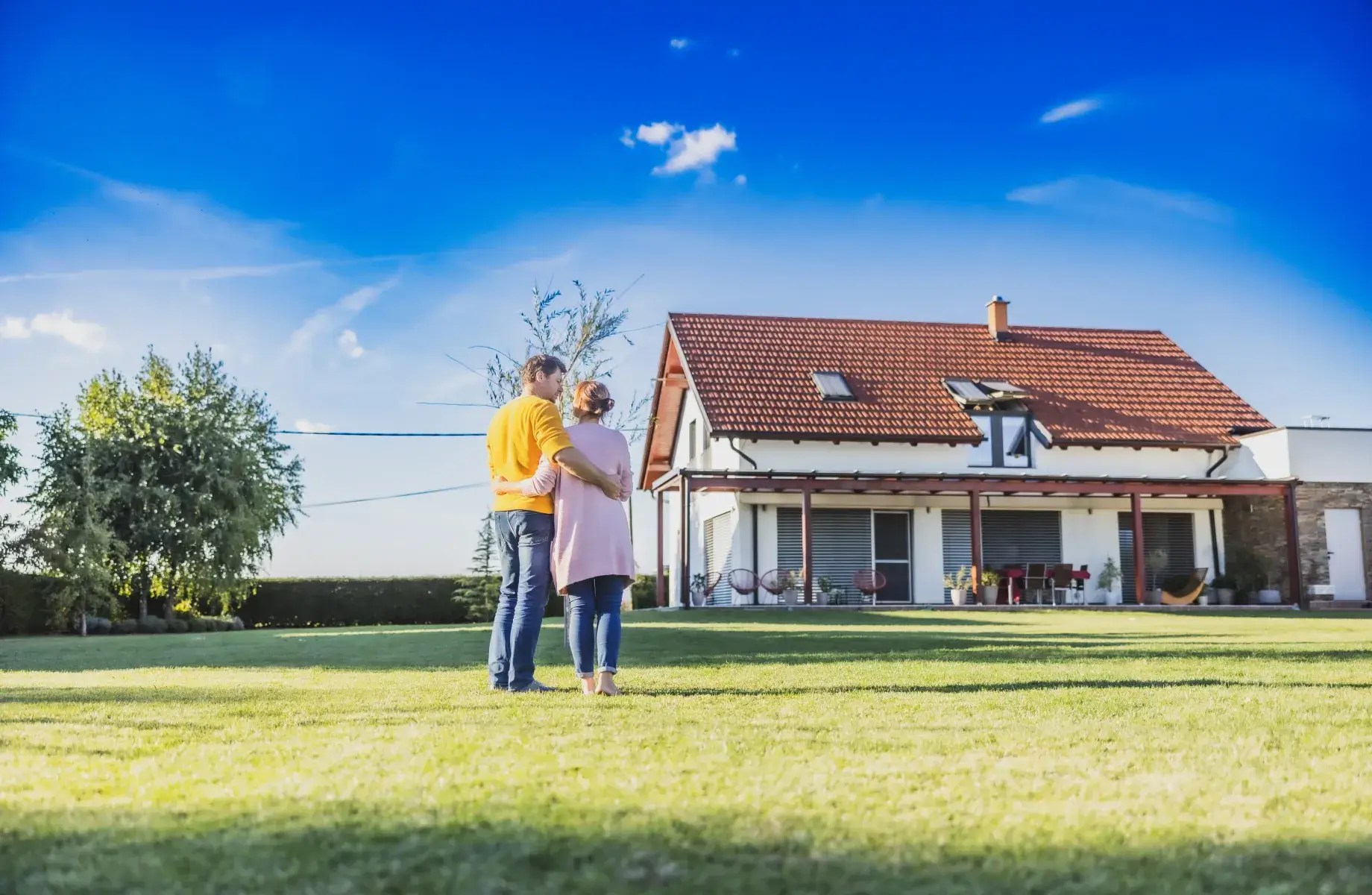 Cuplu în fața unei case conectate la rețeaua electrică, într-o zonă rezidențială.